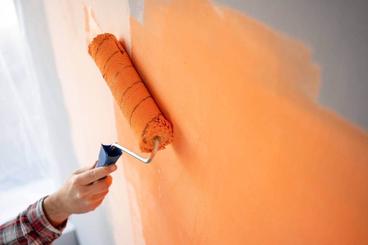 Someone painting a wall orange