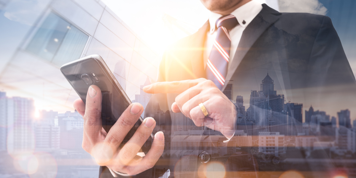 The double exposure image of the business man using a smartphone during sunrise overlay with cityscape image